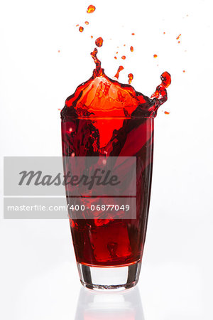 Ices cubes falling in a glass of red liquid on white background