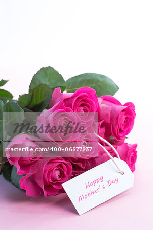 Bouquet of pink roses with happy mothers day card on a light pink table