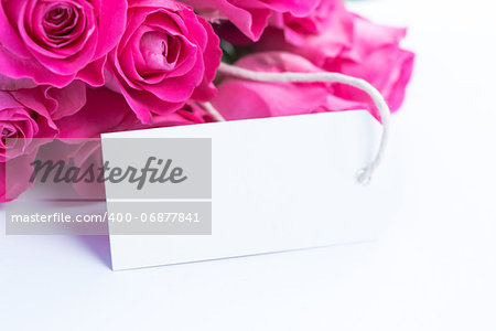 Close up of a beautiful bouquet of pink roses with a blank card on a white table
