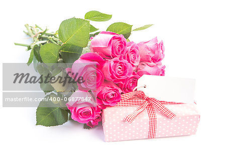 Bouquet of roses next to a gift with a blank card on a white table