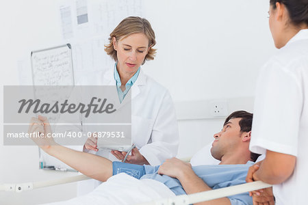 Doctor taking the blood pressure of male patient in hospital