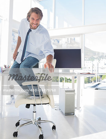 Man surfing his office chair and smiling in modern office