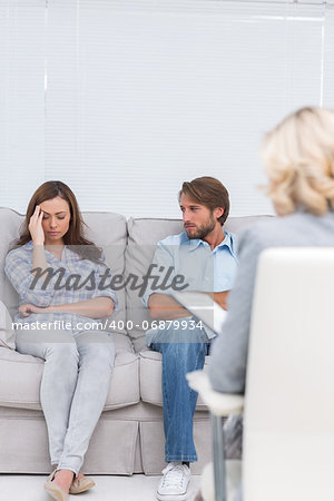 Woman crying on the couch in front of the therapist and her husband