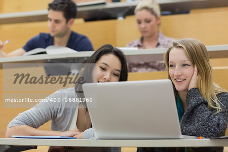 Students sitting in a lecture hall while using the laptop and having fun