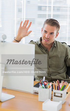 Creative business employee waving in a modern office during a videocall