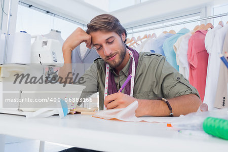 Smiling fashion designer working at his desk in a creative office