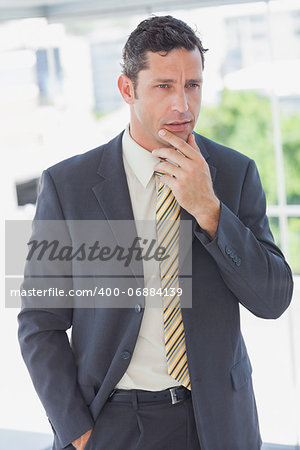 Serious businessman thinking with hand on chin in office
