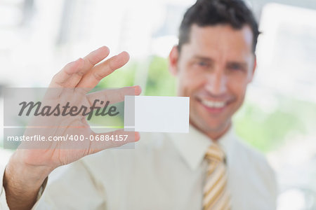 Businessman presenting blank business card in office