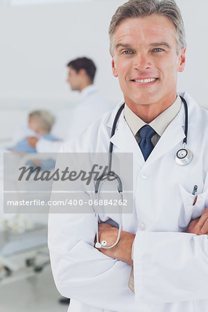 Attractive doctor with arms crossed while doctor taking care of a patient