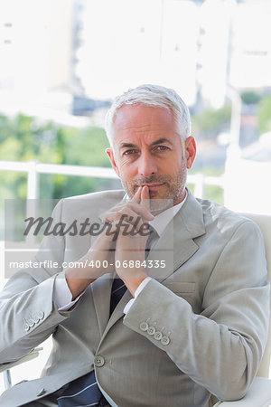 Thoughtful businessman looking at camera in office