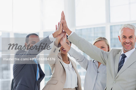 Business team high fiving and smiling at camera in the office