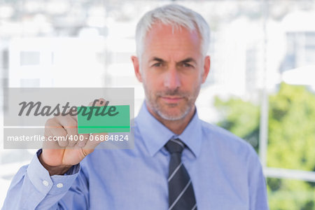 Businessman showing green business card in his office