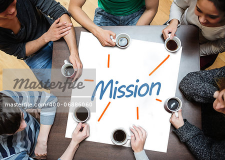 Team brainstorming over a poster on a table with mission written on it