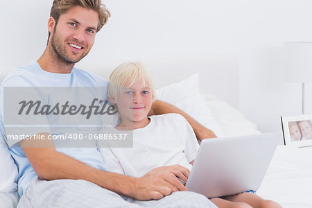 Portrait of a father and his son using a laptop in bed