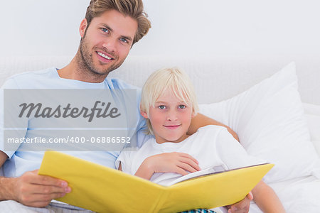 Handsome father reading a story to his son in bed