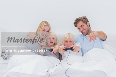 Happy family playing video games in bed