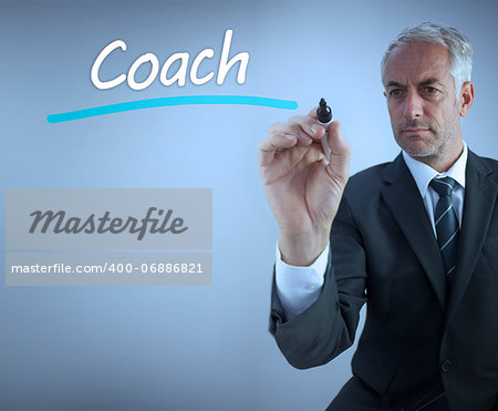 Businessman writing the word coach with a marker