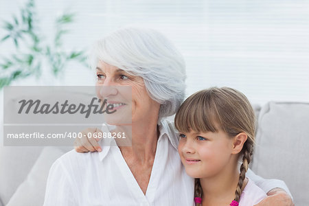 Cute girl and grandmother sitting on the couch in the living room