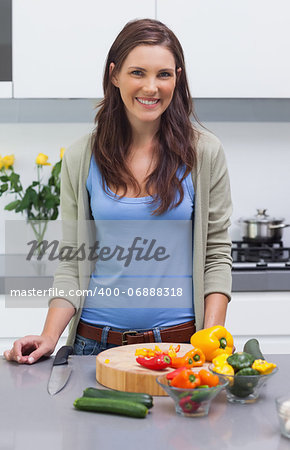 Attractive woman standing in her kitchen in front of sliced vegetables