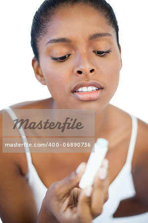 Woman looking at her lip balm on white background