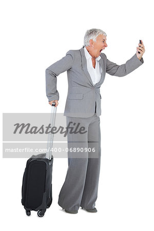 Furious businesswoman screaming during a call with suitcase on white background