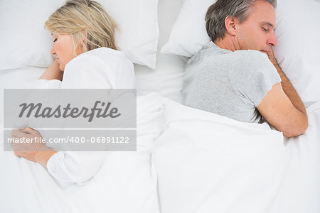 Couple sleeping back to back at home in bed