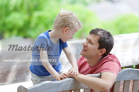 handsome young father looking at his cute son, family of two spending time outdoor