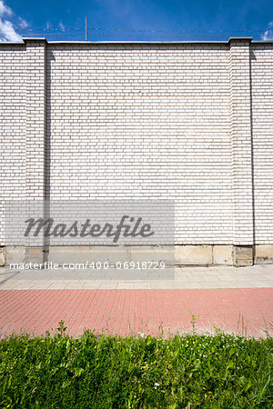 Empty brick wall with a copy space also showing sidewalk, grass and sky