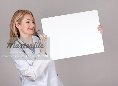 blond female doctor posing on light grey background