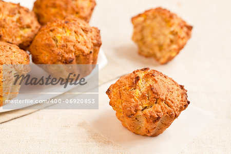 Fresh baked pumkin muffins with one aside.