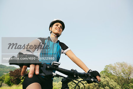 young woman training on mountain bike and cycling in park. Copy space, low angle view