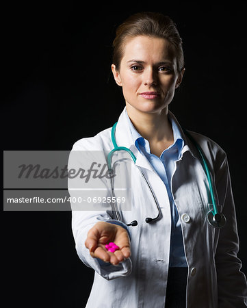 Doctor woman showing pills isolated on black