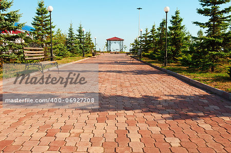 Wide path in nice light  park with benches and summerhouse under clean blue sky