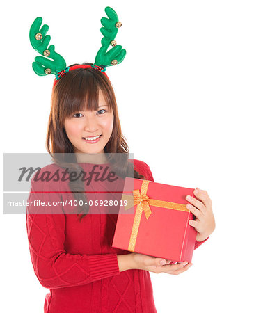 Asian Christmas woman holding gift wearing reindeer horns. Christmas woman portrait of a cute, beautiful smiling Asian Chinese / Japanese model. Isolated on white background.