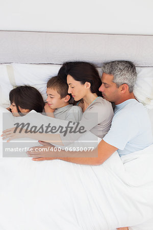 Parent sleeping with their children in bed at home