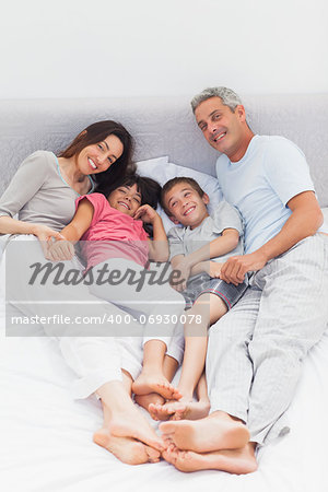 Family lying on bed at home