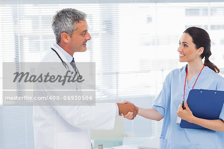 Smiling doctor shaking hands with nurse in medical office