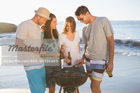 Cheerful young friends having barbecue together on the beach
