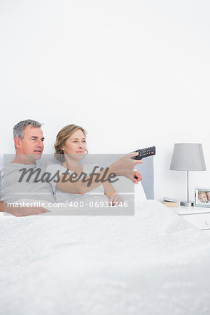 Content couple watching tv in bed at home in bedroom