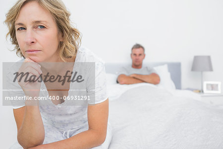 Angry woman looking at camera after fight with husband in bedroom at home