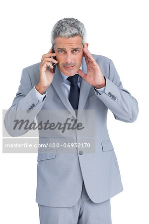Concentrated businessman answering phone against white background