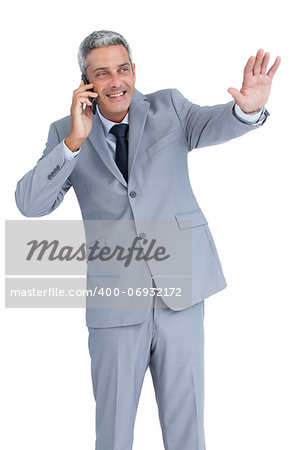 Businessman against white background answering phone and waving