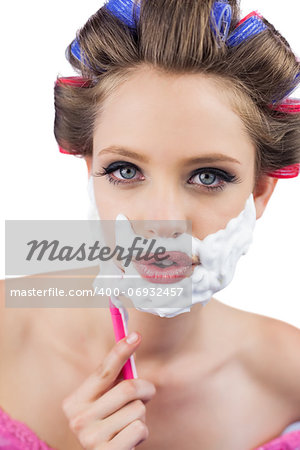 Young model in hair curlers posing with razor in close up