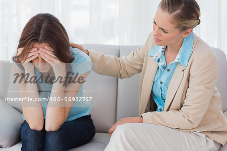 Worried woman being comforted by her therapist and sitting on the couch