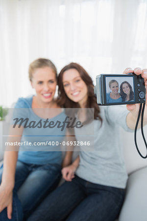 Cheerful friends taking pictures of themselves at home