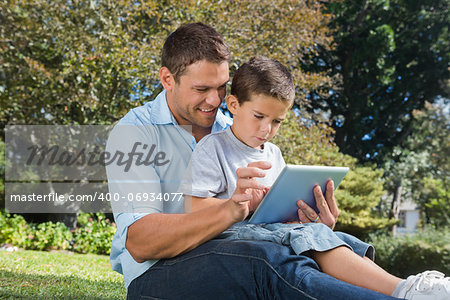 Dad and son using a tablet pc in a park on sunny day