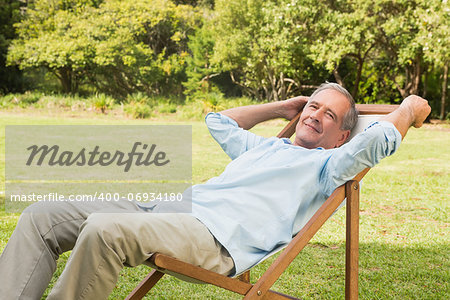 Happy mature man sitting on sun lounger and relaxing in park