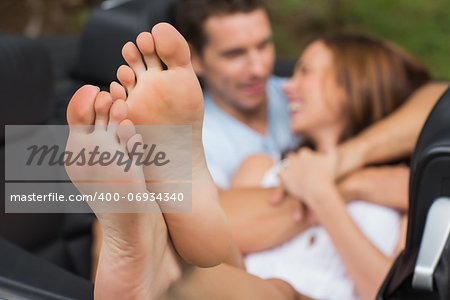Cute couple cuddling in the backseat with focus on foot in a convertible