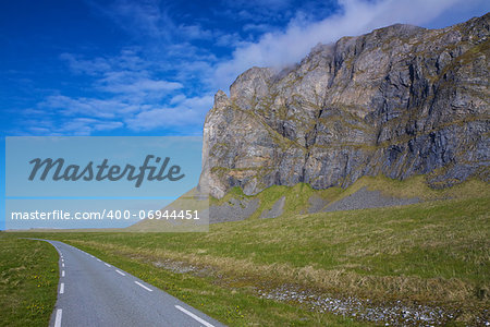 Scenic coastal road under the cliffs of island Vaeroy on Lofoten, Norway
