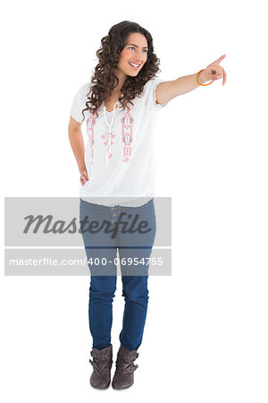 Cheerful attractive brunette wearing casual clothes pointing on white background